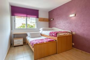 ein Schlafzimmer mit zwei Etagenbetten und einer lila Wand in der Unterkunft Apartamento Coral in Tossa de Mar