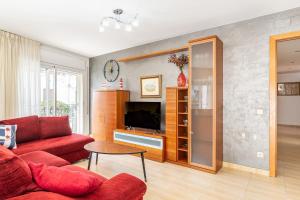ein Wohnzimmer mit einem roten Sofa und einem Fernseher in der Unterkunft Apartamento Coral in Tossa de Mar