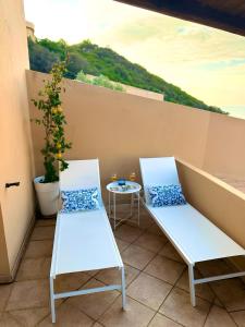 two white chairs on a balcony with a table at Casa il Bouganville - sea view Costa Paradiso in Costa Paradiso