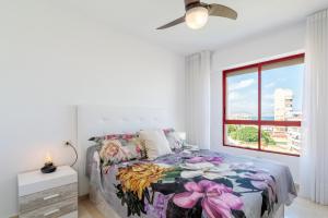 Un dormitorio con una cama con colcha floral y una ventana. en Torre Mar Muchavista, en El Campello 22 fotos más