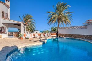 a swimming pool in the backyard of a house with palm trees at Úrsula in Denia