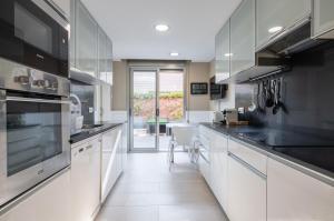 a kitchen with white cabinets and black counter tops at Villa Vidalet solo familias in Cambrils
