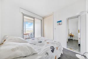 a white bedroom with a bed and a large window at Évasion Océane - Vue mer, Soulac in Soulac-sur-Mer
