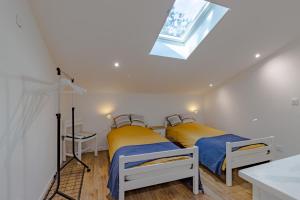 two beds in a white room with a skylight at La Villa du Mas des Chenes in Pomport +23 photos