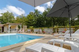 a swimming pool with white chairs and an umbrella at La Villa du Mas des Chenes in Pomport