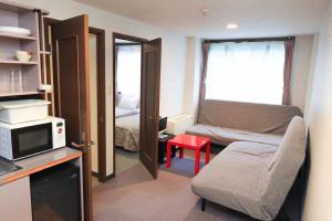 a small room with a bed and a microwave at コンドミニアム白馬五竜 in Hakuba