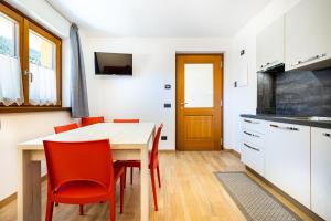 a kitchen and dining room with a table and red chairs at Appartamenti Via Dell'Asilo in Isolaccia