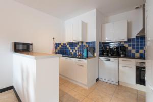 una cocina con armarios blancos y azulejos azules en la pared en Gite St Marie De Campan, en Sainte-Marie-de-Campan