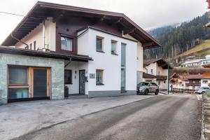 une maison blanche avec une voiture garée dans la rue dans l'établissement Apart-hochzillertal Gartenwohnung, à Kaltenbach