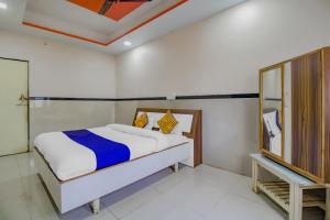 a bedroom with a bed and a mirror at SPOT ON Indirasagar Executive in Kolhapur