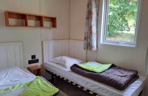 zwei Betten in einem Zimmer mit Fenster in der Unterkunft Camping les Pialades -Chalet Mimosa in La Mouline