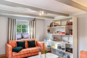 a living room with an orange chair and bookshelves at Haus Deichperle Tini Anton in Dornum