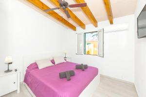 a bedroom with a purple bed in a white room at Las siete palmeras - ciudadela in Cala en Blanes +16 photos