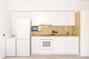 a kitchen with white cabinets and a refrigerator at Las siete palmeras - ciudadela in Cala en Blanes