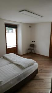 a white bedroom with a bed and a window at Appartamento Via Livigno in Isolaccia