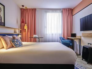 ジュヌヴィリエにあるIbis Styles Paris Gennevilliersの大きなベッドと机があるホテルの部屋