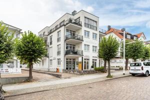 un bâtiment blanc dans une rue avec une voiture garée devant dans l'établissement Wohnung Wilma - Villa Wiederkehr, à Sellin