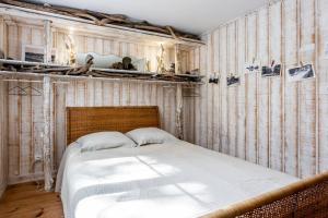 Un dormitorio con una cama y una pared de madera. en La Cabane de Bébert - Marie en Lys, en Cap-Ferret