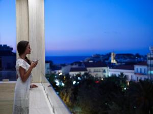 Una donna in abito bianco con un bicchiere di vino in mano di Samaria Hotel a Chania