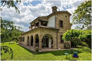 an old brick building with a tower on a grass field at Italian Experience-Villa Incanto in Potenza Picena