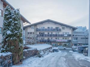 un parking couvert de neige en face d'un bâtiment dans l'établissement Tirola Platzl, à Hopfgarten im Brixental