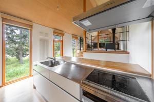 une cuisine avec un évier et une cuisinière dans l'établissement Poroto House, à Nanae 156 autres photos