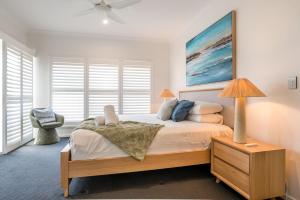 een slaapkamer met een bed met een lamp en een stoel bij Luxury Pool Home Near Noosa & Coolum Sleeps 8 in Peregian Springs +34 foto's