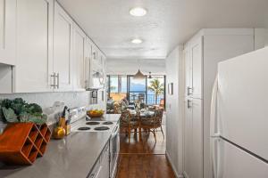 a kitchen with white cabinets and a dining room at Lauloa 303 in Maalaea