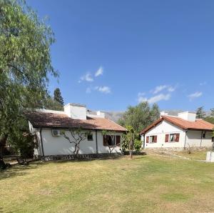 a white house with a large yard in front of it at Cabañas Aldea Blanca in Merlo