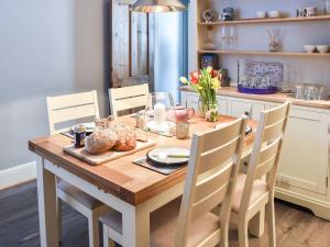 een eettafel met stoelen en een houten tafel bij Fuchsia Cottage in Sea Palling