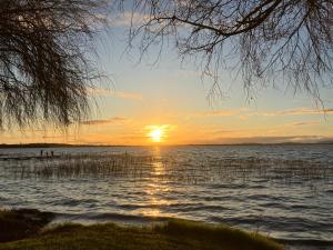 a sunset over a body of water with the sun setting at Lake Colac Holiday Park in Colac