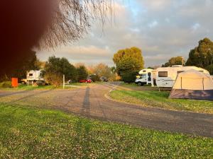 a campsite with tents and a dirt road at Lake Colac Holiday Park in Colac +5 photos
