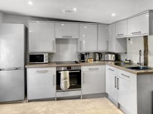 カンタベリーにあるThe Friars Apartment, Eastbridge Hospitalの白いキャビネットとステンレス製の電化製品を備えたキッチン