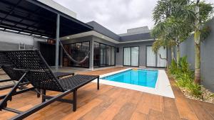 ein Haus mit einem Pool und einem Stuhl in der Unterkunft Casa em Foz do Iguaçu com piscina, churrasqueira e natureza ao redor para sua família in Foz do Iguaçu