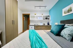 a bedroom with a bed with blue walls and a kitchen at Moderno com piscina e perto da praia in Rio de Janeiro +73 photos