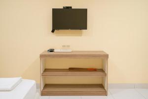 a television on a wall next to a bed at RedDoorz at Hotel Galuh Putra Pangandaran in Pangandaran