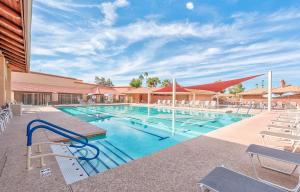 a swimming pool with white chairs and a building at At Your Leisure in Mesa