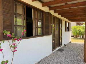 eine Veranda eines Hauses mit Fenstern und Blumen in der Unterkunft Las chochitas 6p in Punta Del Diablo