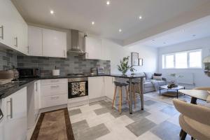 a kitchen with white cabinets and a living room at Designer 1BR I Work-From-Home Ready I Fast Wi-Fi in Slades Green