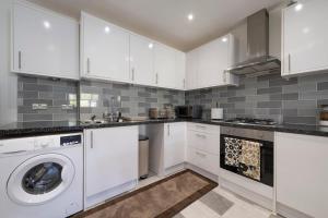 a kitchen with white cabinets and a washer and dryer at Designer 1BR I Work-From-Home Ready I Fast Wi-Fi in Slades Green +40 photos