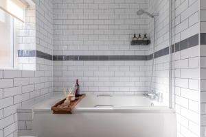 a bath tub in a white tiled bathroom at Designer 1BR I Work-From-Home Ready I Fast Wi-Fi in Slades Green
