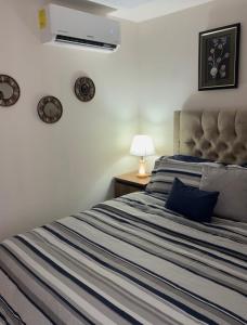 a bedroom with a bed with a blue and white striped blanket at Cozy & Modern Apartment in Lirios de Miraflores in Tegucigalpa