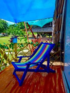 a blue chair sitting on a deck under an umbrella at Glamping Tesoro Escondido in San Antero +1 photo
