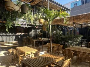 ein Restaurant mit Holztischen und Stühlen und einer Palme in der Unterkunft La Selva Hostel in Mexiko-Stadt
