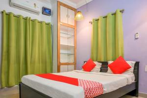 a bedroom with a bed with green curtains and red pillows at Hotel O DREAM INN in Khandagiri