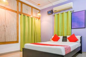 a bedroom with a bed with green and red pillows at Hotel O DREAM INN in Khandagiri