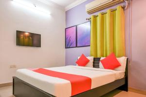 a bedroom with a bed with red and orange pillows at Hotel O DREAM INN in Khandagiri +22 photos