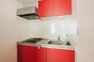 eine Küche mit roten Schränken und einer Spüle in der Unterkunft Ｂｒａｎｃｈｅ住吉ＥＡＳＴ in Fukuoka + 45 Fotos