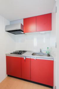eine Küche mit roten Schränken und einer Spüle in der Unterkunft Ｂｒａｎｃｈｅ住吉ＥＡＳＴ in Fukuoka