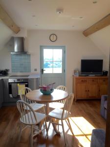 a kitchen with a table and chairs and a clock on the wall at The Barn - Nr Bromyard in Bromyard